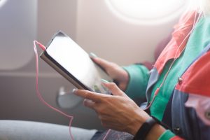 A young woman uses a tablet on the plane. Reading an e-book while traveling. Airplane passenger.
