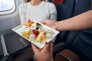 Airline stewardess giving plate with snacks to passenger