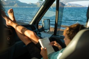 Kid with book resting in car near sea