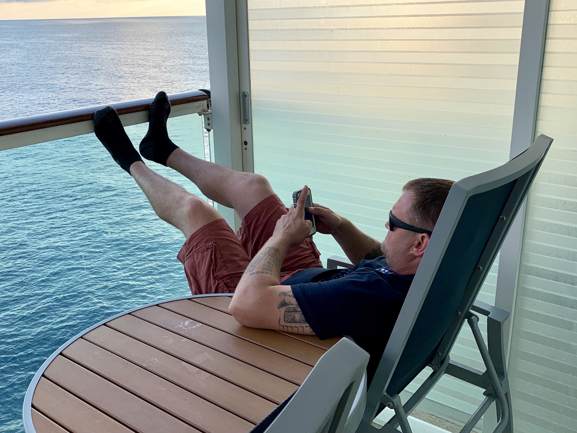 Man texting on balcony on a cruise ship