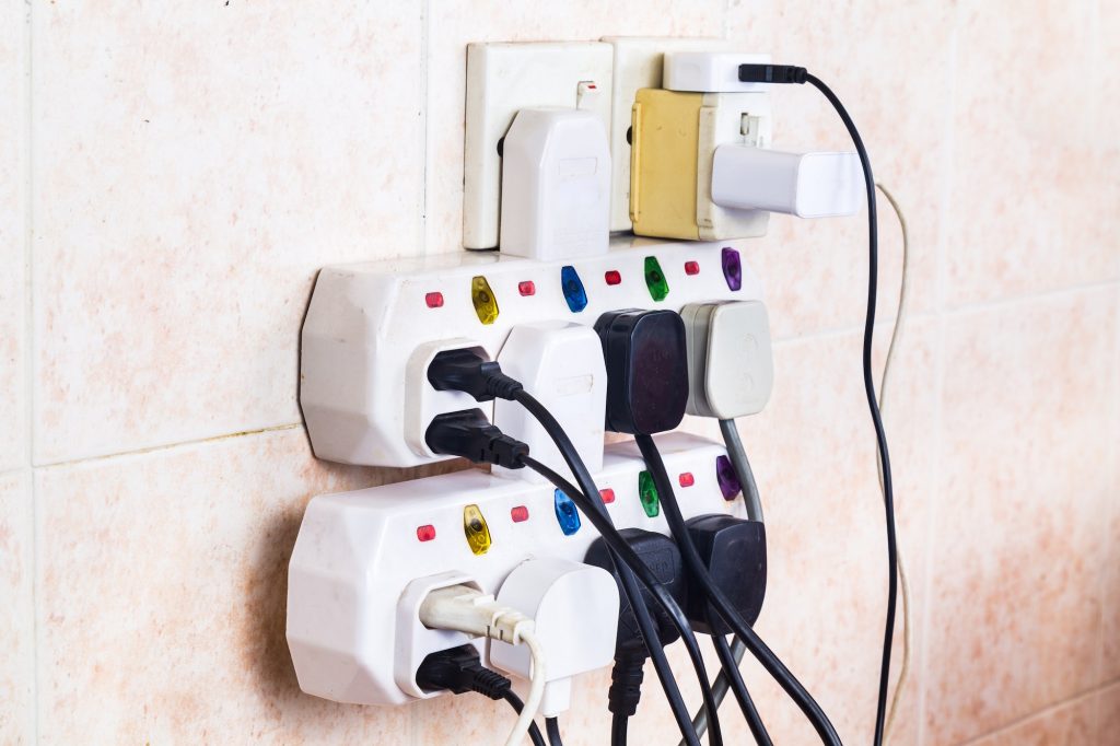 Multiple electricity plugs on adapter risk overloading and dange