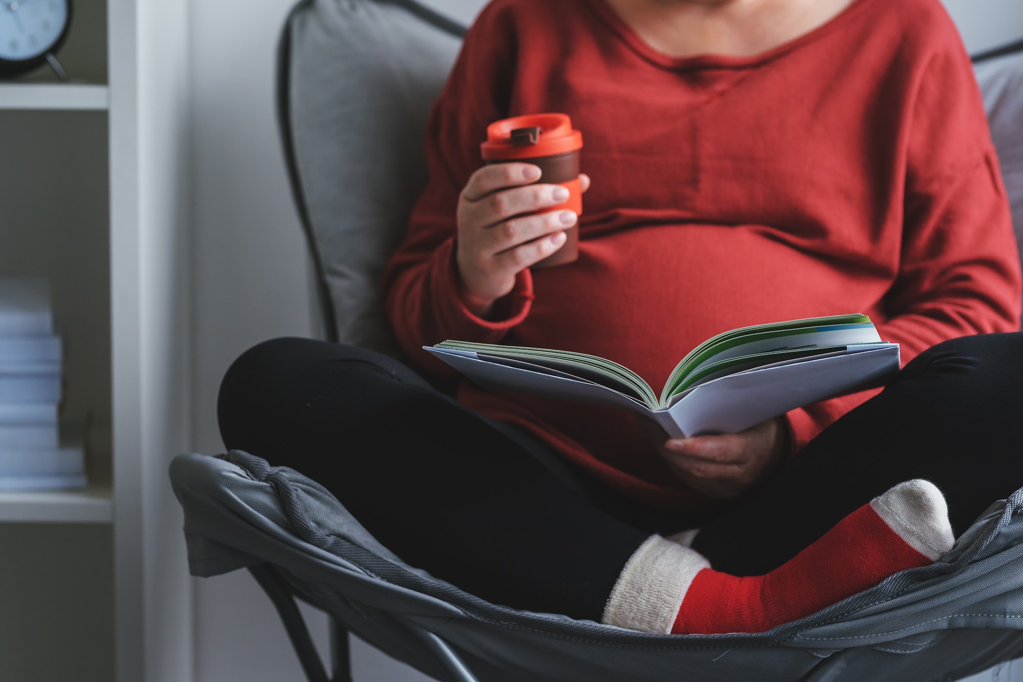 Pregnant woman reading book in living room