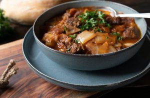 Romanian beef stew with cabbage and vegetables on wooden background