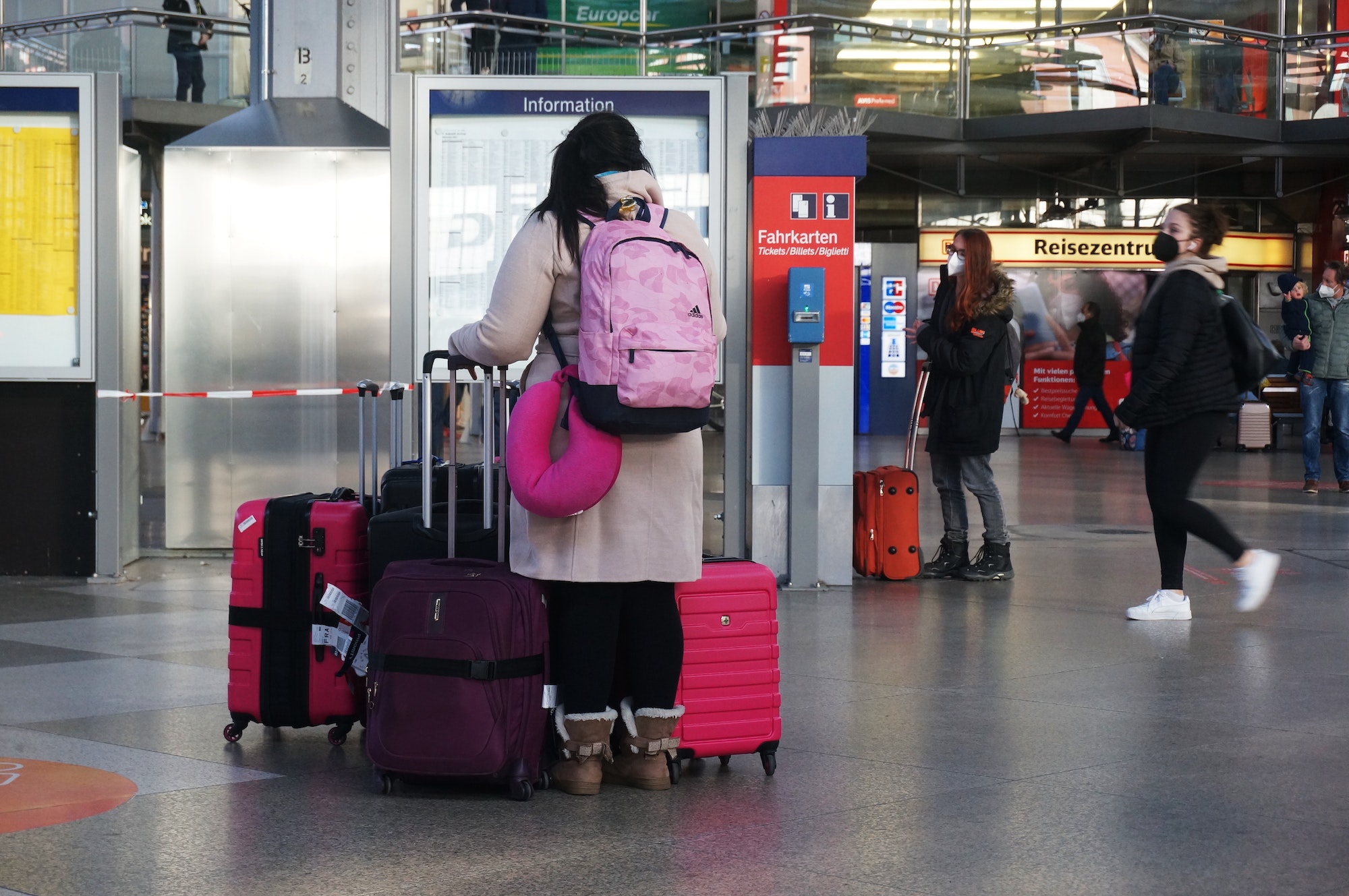 Woman traveling, waiting at Düsseldorf Central station, carrying a lot of pink luggage.
